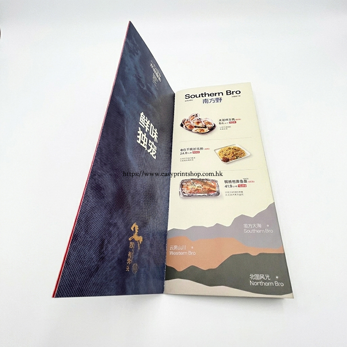 A side-view of the folded brochure, showcasing the internal menu layout, food imagery, and printed text details on a textured blue background A side-view of the folded brochure, showcasing the internal menu layout, food imagery, and printed text details on a textured blue background