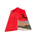 An-angled-view-of-the-brochures-exterior-featuring-a-vibrant-red-cover-with-a-prominent-black-horse-silhouette-graphic-and-mountain-themed-print-design